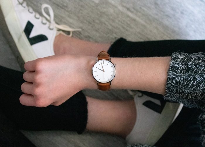 Woman sitting with leather watch and white sneakers